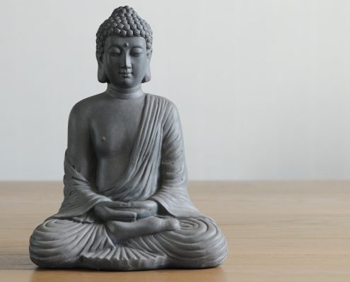 Graue Buddhafigur auf Holz mit weißem Hintergrund