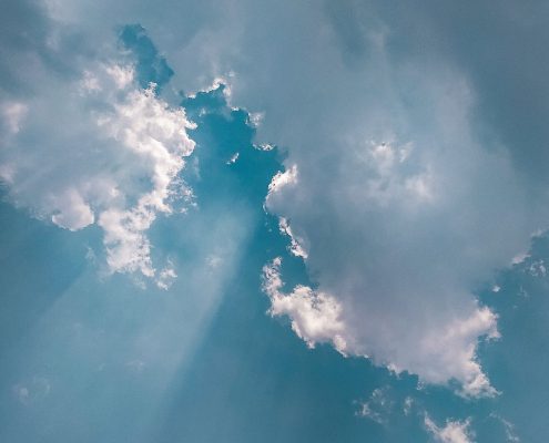 Blauer Himmel mit Wolken und Sonnenstrahlen